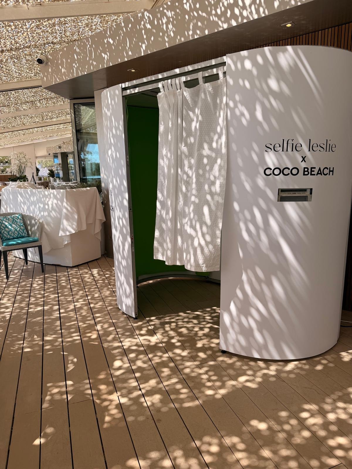 Side view of white photo booth cabin on wooden terrace at Coco Beach Ibiza brand event
